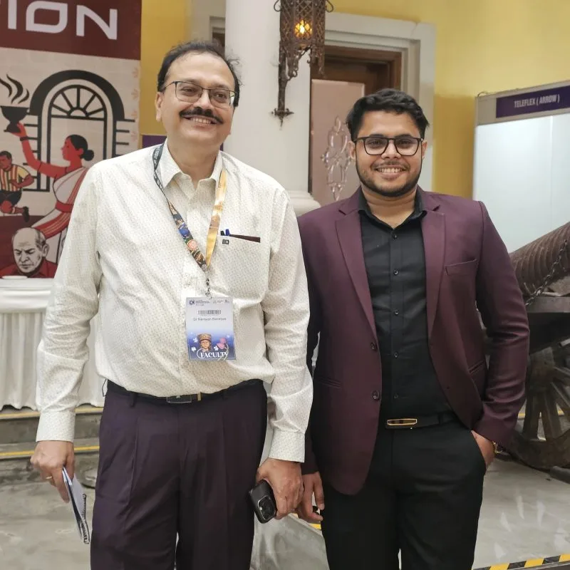 Dr. Narayan Banerjee, wearing a conference faculty badge and holding a printed copy of Rules Before Reach, beside a Medmatis team member