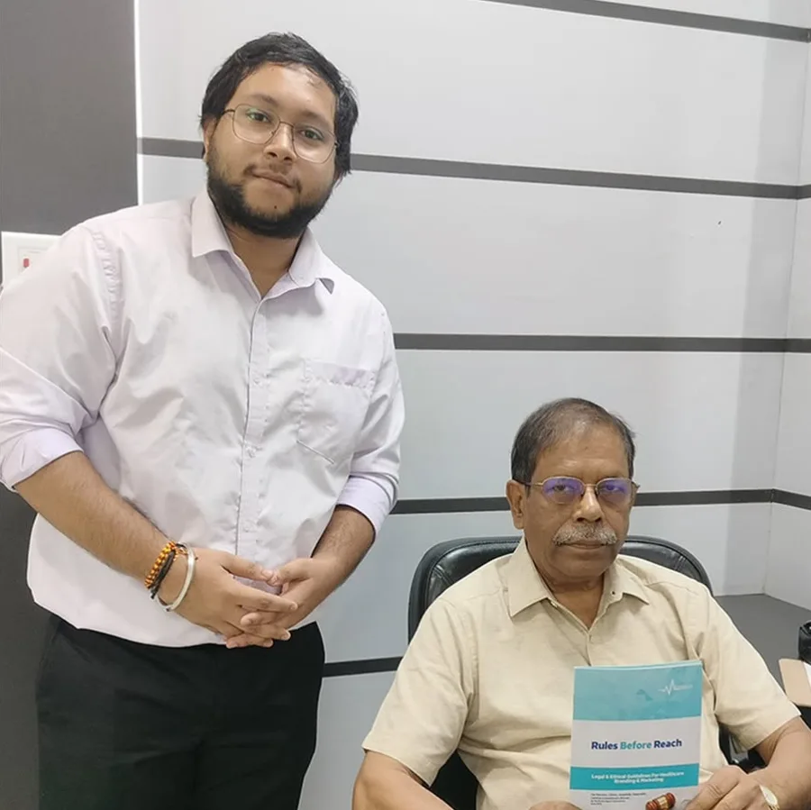 Prof. Dr. D. P. Sinha holding a printed copy of Rules Before Reach, with a Medmatis team member standing beside him